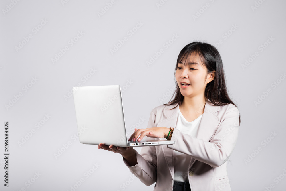 Woman smiling confident smiling holding using laptop computer and typing keyboard for online sending email or chat, Portrait excited happy Asian young female studio shot isolated on white background Woman smiling confident smiling holding using laptop computer and typing keyboard for online sending email or chat, Portrait excited happy Asian young female studio shot isolated on white background