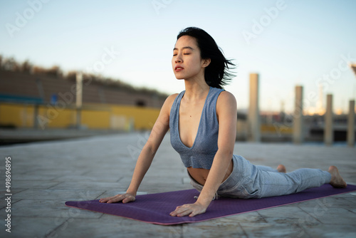 Beautiful young woman stretching outside. Fit woman doing yoga exercise.