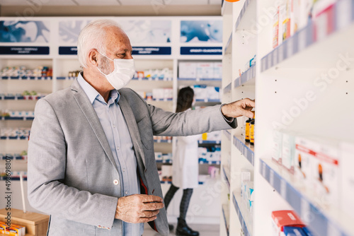 An old man choosing vitamins and supplements during covid 19.