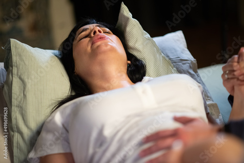 Pregnant woman during birth contractions. Dark-haired woman feeling pain during giving birth at home. Home-birth, childbirth, emotion concept