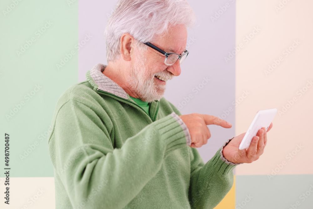 Smiling confident male video chat with digital tablet held in his hands standing on cute background. White-haired mature caucasian man with glasses, college student of the third age university Smiling confident male video chat with digital tablet held in his hands standing on cute background. White-haired mature caucasian man with glasses, college student of the third age university