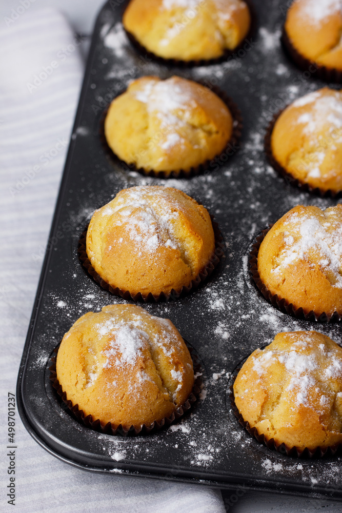 Baking tray with baked muffins on wooden white background.