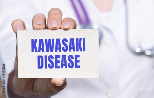 Doctor in white medical clothes with a stethoscope showing a paper card with words Kawasaki disease. Medical concept. photo