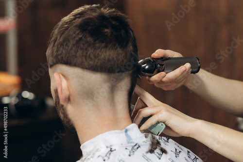 Back view of Men in beauty salon. Men's haircut in a barbershop. Professional hairdresser uses a hair clipper for fringing hair