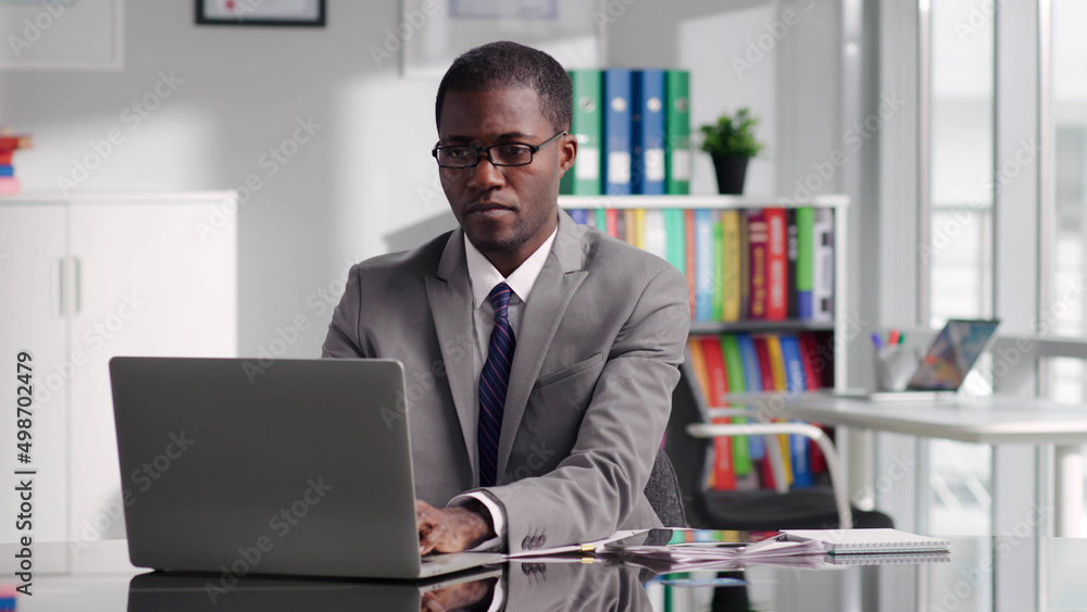 Portrait of successful African-American politician working on laptop in modern white workspace Portrait of successful African-American politician working on laptop in modern white workspace