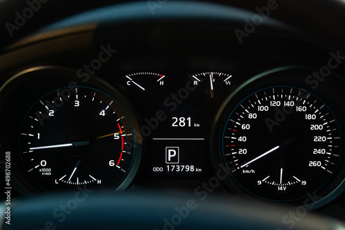 Modern car illuminated dashboard closeup. White arrows on Speedometer