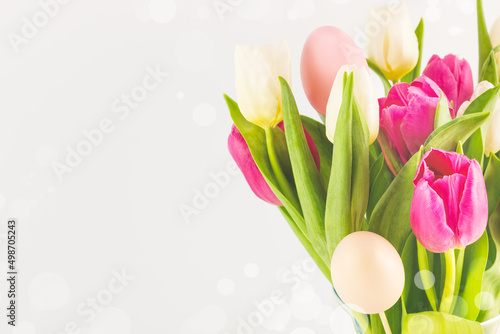 Fototapeta Naklejka Na Ścianę i Meble -  Holiday Easter card with beautiful spring bouquet of white and pink tulips with decorative easter eggs on a white background with copy space suitable for congratulation or invitation. Soft focus style