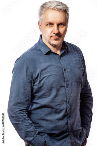 Portrait of a bearded middle-aged man looking thoughtfully at the camera over a white studio background with copy space