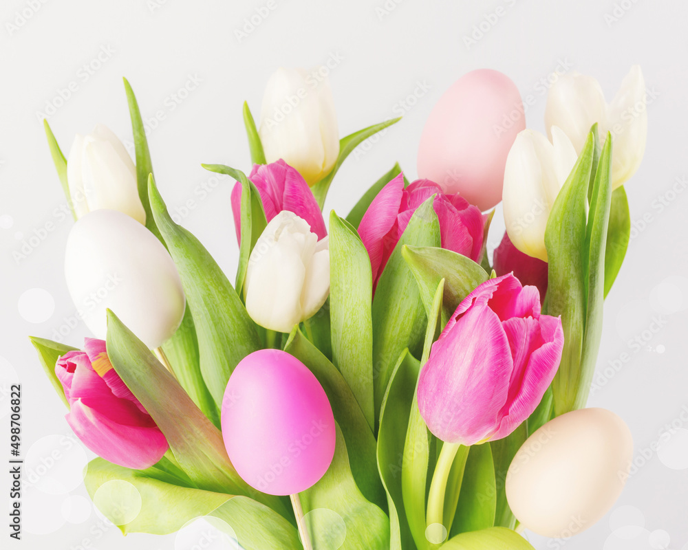 Easter holiday composition with beautiful spring bouquet of white and pink tulips with decorative easter eggs on a white background with bokeh effect. Soft focus style