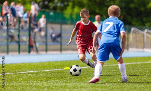 Teenage boy running with soccer ball during tournament game. European football match between school teams. Sporty kids kicking ball