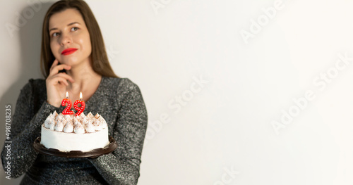 Thoughtful woman holding birthday cake relaxed thinking about something looking at a copy space
