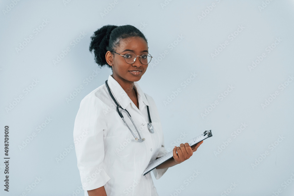 Standing with stethoscope. Young african american woman is against white background Standing with stethoscope. Young african american woman is against white background