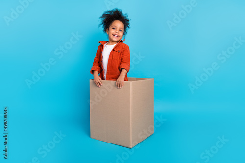 Full body photo of funky wavy small girl in box wear brown shirt isolated on blue color background