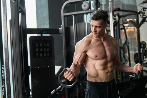 Muscular man working out in gym, strong male torso abs.