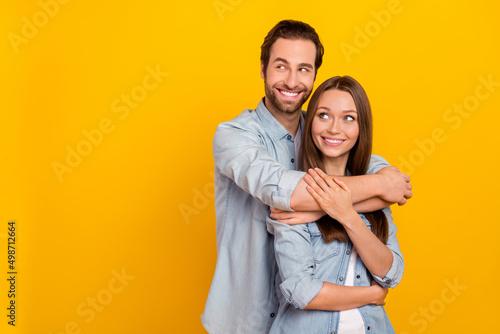 Portrait of attractive cheerful dreamy couple hugging looking idea copy space isolated over bright yellow color background