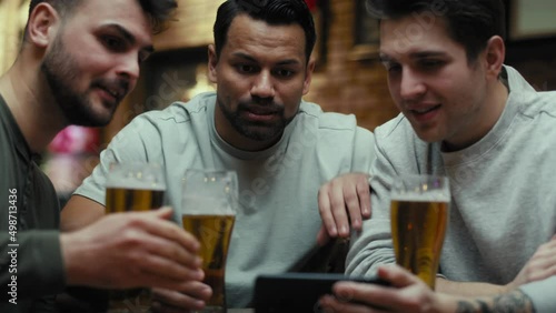 Three male friends watching football match on phone in the pub. Shot with RED helium camera in 8K.