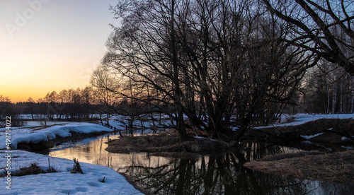 Fototapeta Naklejka Na Ścianę i Meble -  Dramatic sunset view over the river in winter; colorful sky and soft evening light; trees are reflected in the water