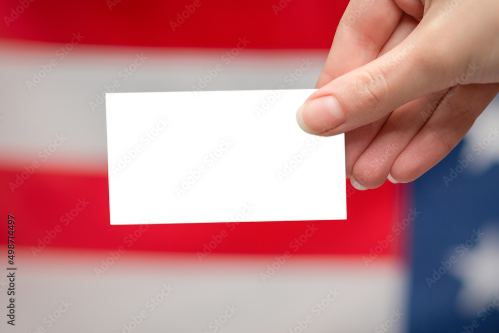 Empty card in woman hand. Copy space. American flag background. Empty card in woman hand. Copy space. American flag background.