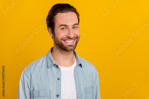 Photo of pretty attractive young man wear jeans shirt smiling empty space isolated yellow color background
