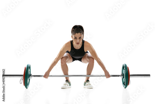 Studio shot of young woman in sportswear exercising with a weight, barbell isolated on white background. Sport, weightlifting concept