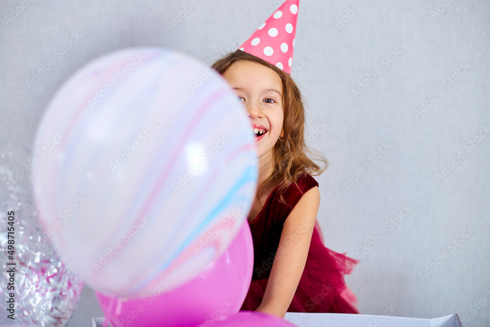 Portrait of cute, Joyful little girl in pink dress and hat play with balloons at home