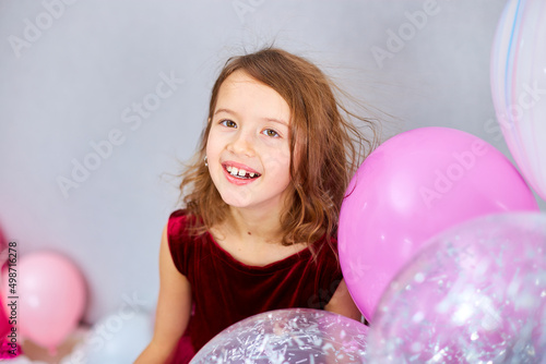 Cute, Joyful little girl in pink dress and hat play with balloons at home birthday party