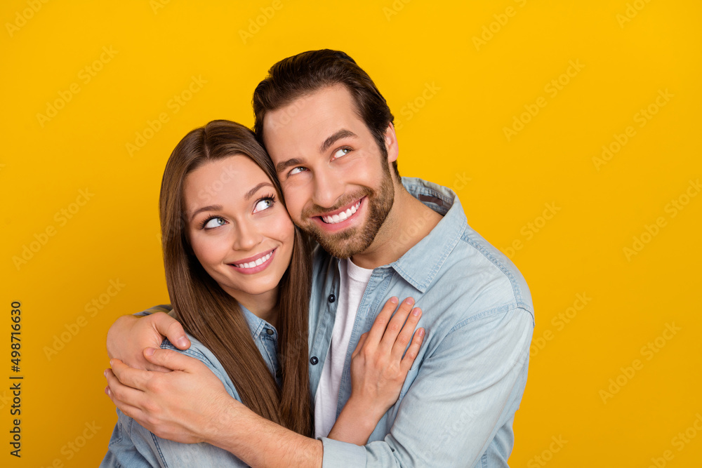 Photo of dreamy funny husband wife wear jeans shirts cuddling looking empty space isolated yellow color background Photo of dreamy funny husband wife wear jeans shirts cuddling looking empty space isolated yellow color background