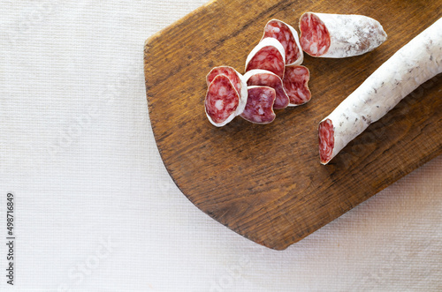 Traditional Catalan thin sausage - fuet. Slices Pork sausage with mold on a wooden cutting board. The concept of traditional food. Horizontal orientation. Top view. copy space.