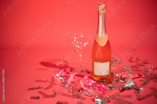 Rose wine and glass. Bottle of rose champagne sparkling wine on pink background with celebration confetti. photo