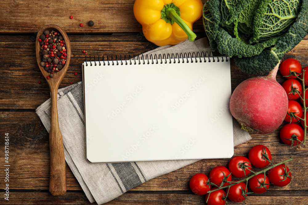 Recipe book surrounded by different ingredients on wooden table, flat lay with space for text. Cooking classes Recipe book surrounded by different ingredients on wooden table, flat lay with space for text. Cooking classes