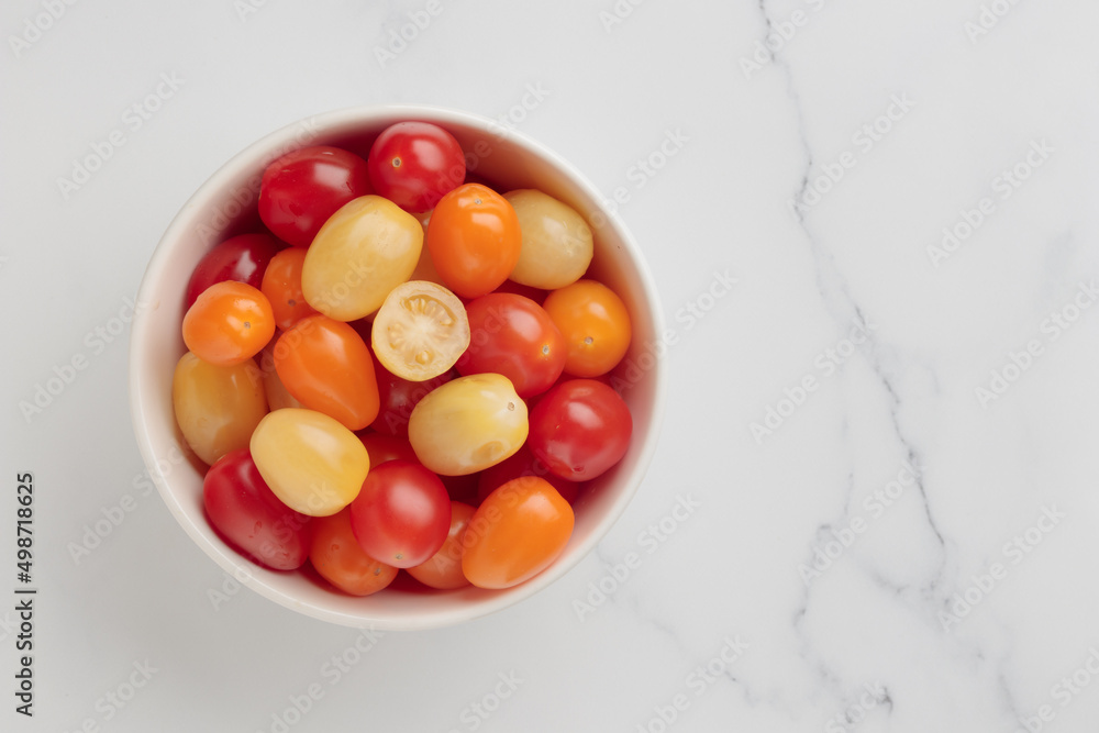 Yellow, orange and red cherry tomatoes in a white bowl Yellow, orange and red cherry tomatoes in a white bowl