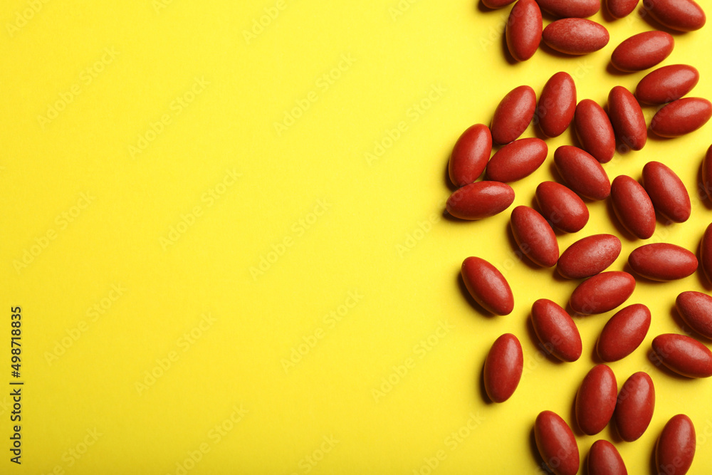 Red pills on yellow background, flat lay with space for text. Anemia treatment Red pills on yellow background, flat lay with space for text. Anemia treatment