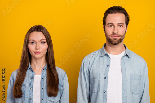 Photo of serious confident sister brother dressed denim shirts smiling isolated yellow color background