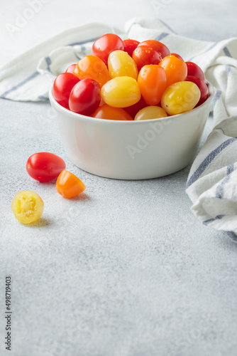 Yellow  orange and red cherry tomatoes in a white bowl