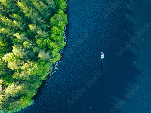 Fototapeta Naklejka Na Ścianę i Meble -  Aerial view of blue lake with fishing boat and green woods in Finland