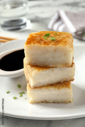 Plate with turnip cake on white marble table, closeup