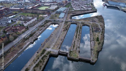Aerial image over the River Clyde towards Govan in Glasgow, Scotland. A bright sunny day with sky reflections in unused docks giving appearance of huge arched windows like a cathedral. photo