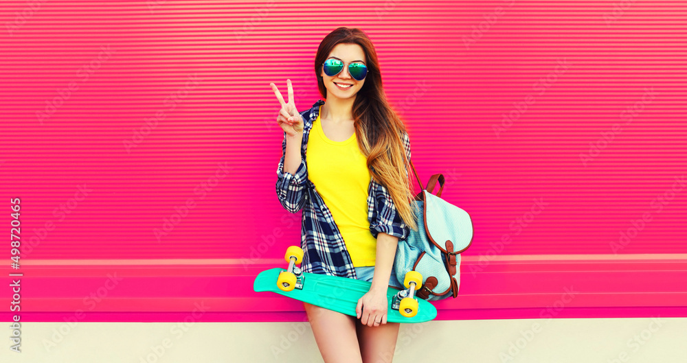 Portrait of happy smiling young woman with skateboard wearing colorful on vivid background
