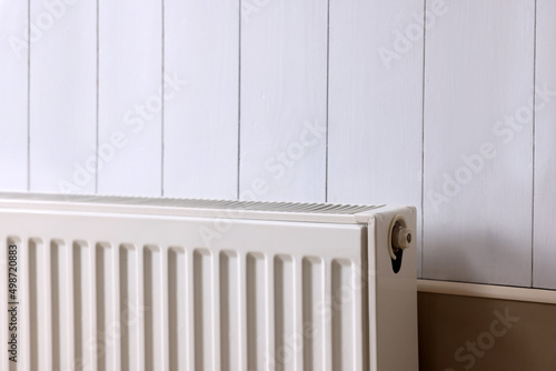 Modern radiator on white wooden wall. Central heating system