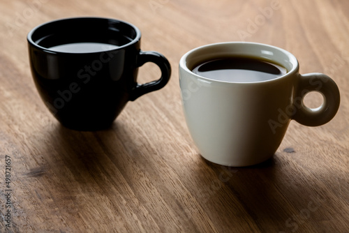 Two black and white coffee cups on wooden background