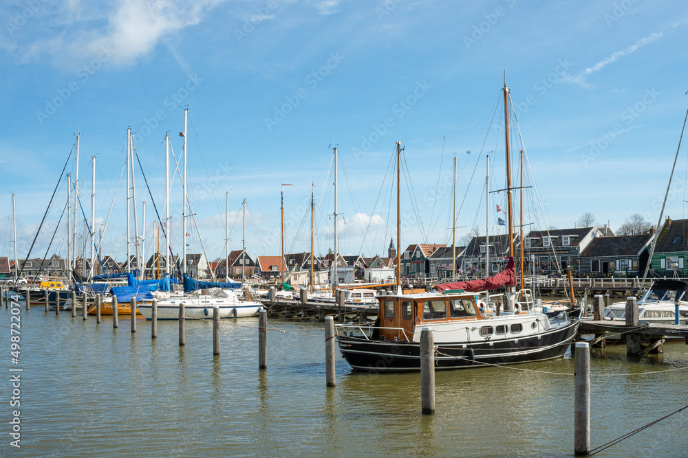 Yachts moored in the harbor in the Dutch countryside in early spring against the blue sky.