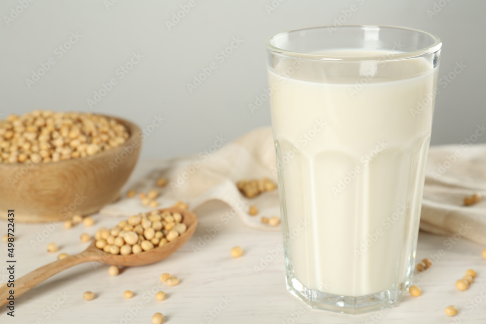Glass with fresh soy milk and grains on white wooden table, closeup Glass with fresh soy milk and grains on white wooden table, closeup
