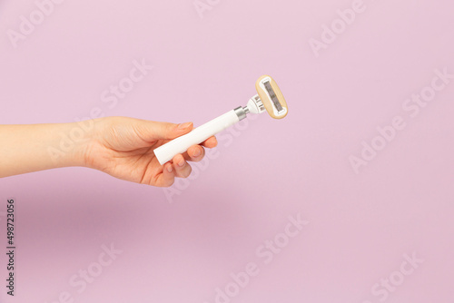 girl holding razor in hand on pink background
