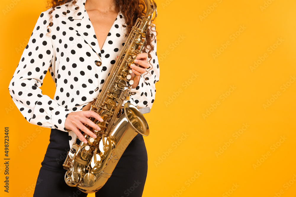 Naklejka premium African American woman with saxophone on yellow background. Space for text