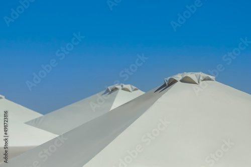 Beach umbrellas against blue sky on sunny day  closeup