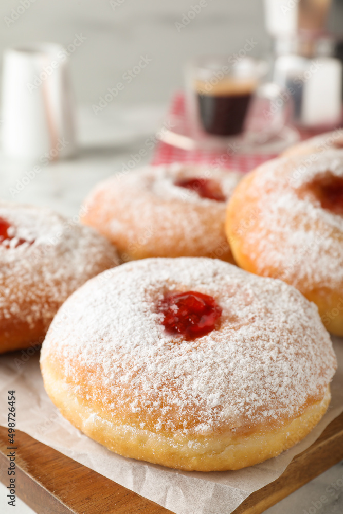 Delicious donuts with jam and powdered sugar on wooden board, closeup