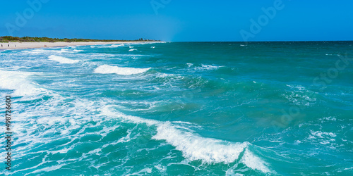 Panorama of the Atlantic Ocean in sunny windy weather. Beautiful green waves crash on a sandy beach in Florida