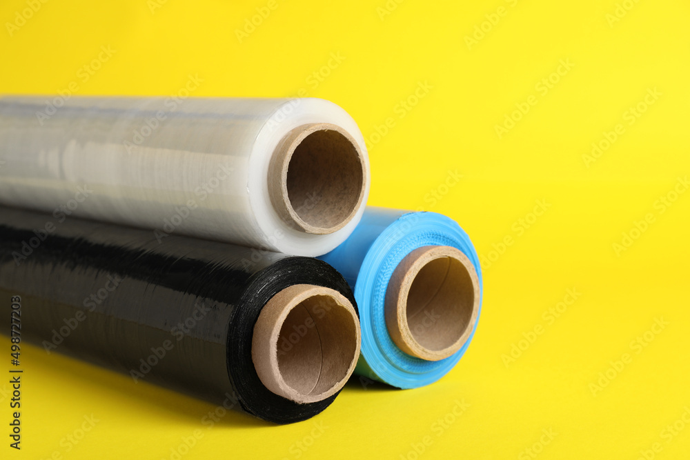 Rolls of different stretch wrap on yellow background, closeup Rolls of different stretch wrap on yellow background, closeup