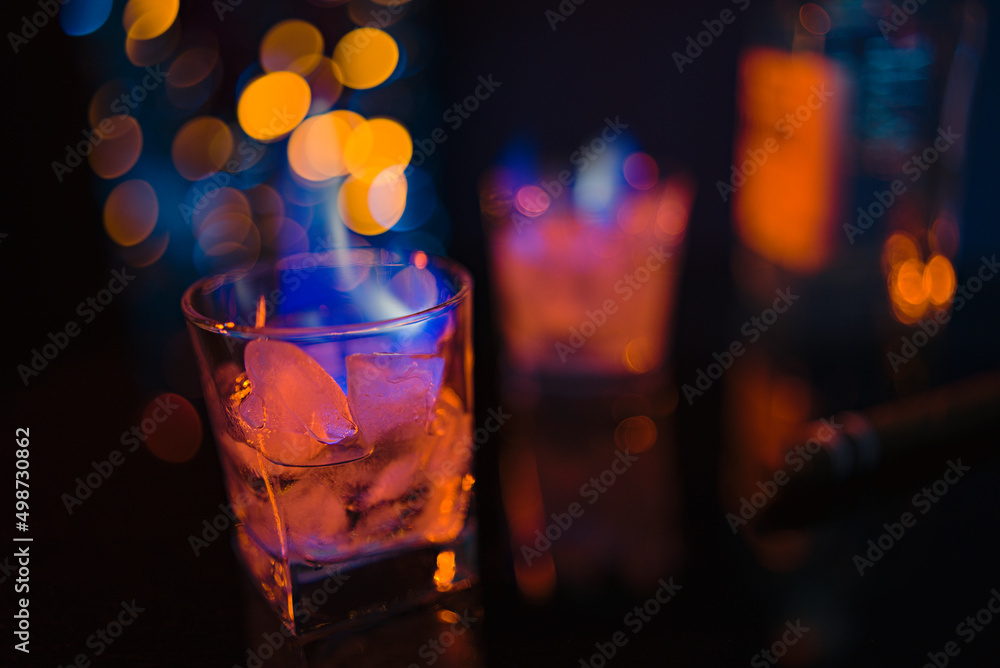 Flames in two glasses with strong alcohol on the bar counter. In glasses with ice and a strong drink, the fire burns with orange and blue flames. Flames in two glasses with strong alcohol on the bar counter. In glasses with ice and a strong drink, the fire burns with orange and blue flames.
