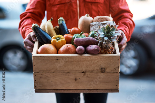 Delivered fresh right to your door. Cropped shot of a man delivering a crate full of fruit and vegetables.